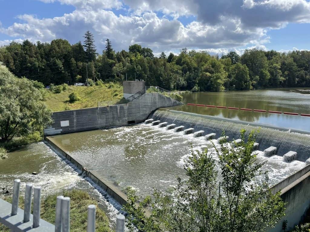 Dam with water flow in a scenic outdoor setting, showcasing infrastructure and natural landscape, suitable for demonstrating moving services near water or riverfront locations.