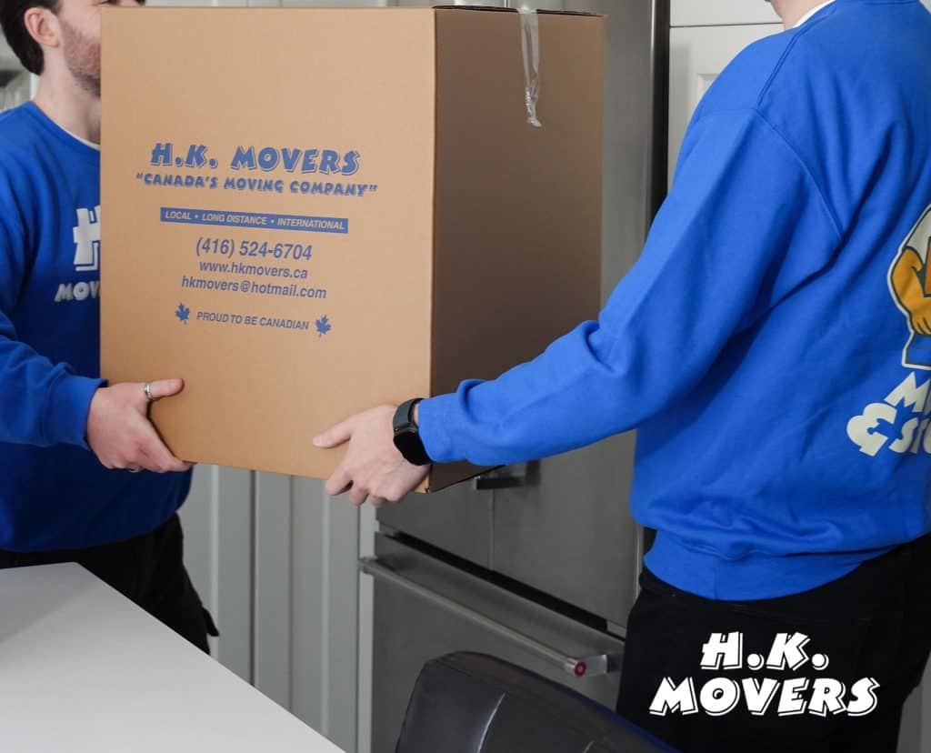 Movers carrying a large H.K. Movers box