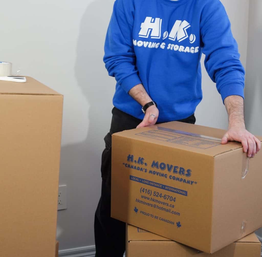 Professional mover handling a box in Oshawa for local moving services. Reliable and affordable moving solutions by HK Movers.